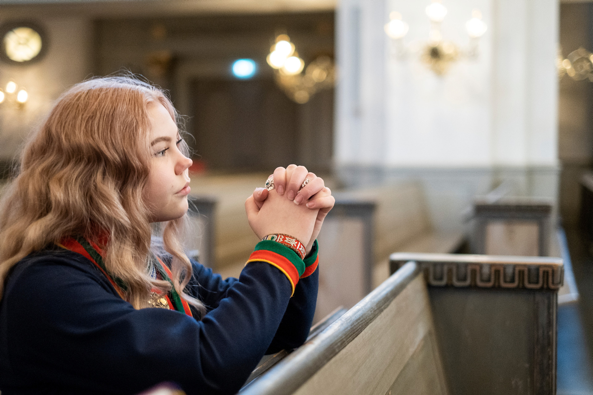 Flicka ber i kyrka och bär traditionella samekläder
