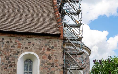 Byggnadsställning uppställd för renovering längs korsidan av Gamla Uppsala kyrka