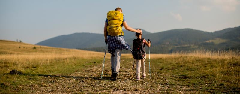 En förälder på vandring i naturen med sitt barn.