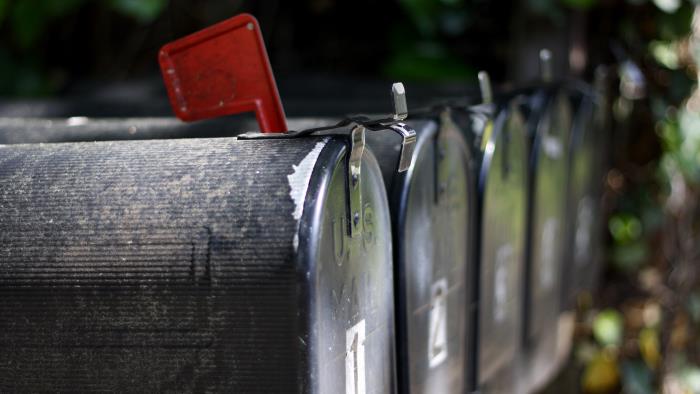 Svarta postlådor på rad med röd flagga för att markera att kommit finns post