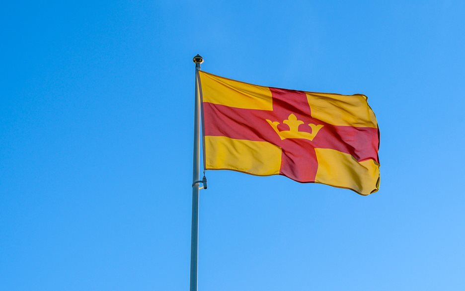 Svenska kyrkans flagga mot blå himmel.