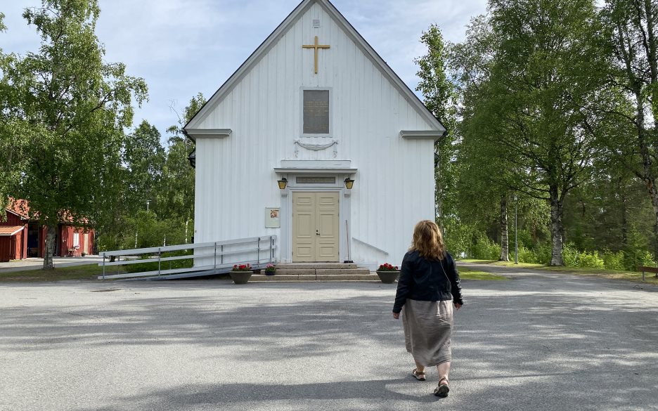 Kvinna på väg mot ingången till en träkyrka.