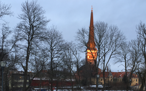 Domkyrkan i Västerås återspeglas i vattnet en vintereftermiddag i skymning.