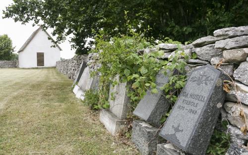 Några gravstenar står lutade mot en stenmur.