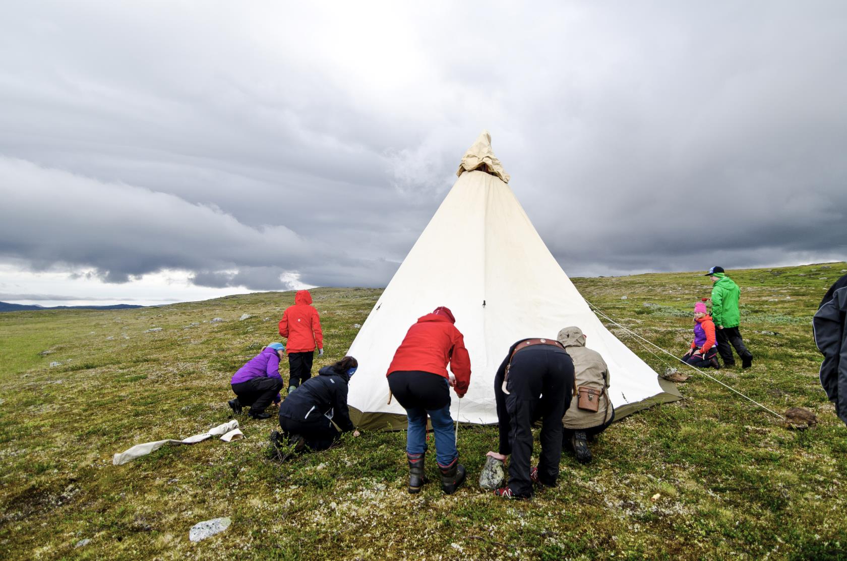 En grupp människor sätter upp ett tält på fjället.