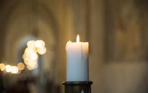 Ett tänt stearinljus i en kyrka.