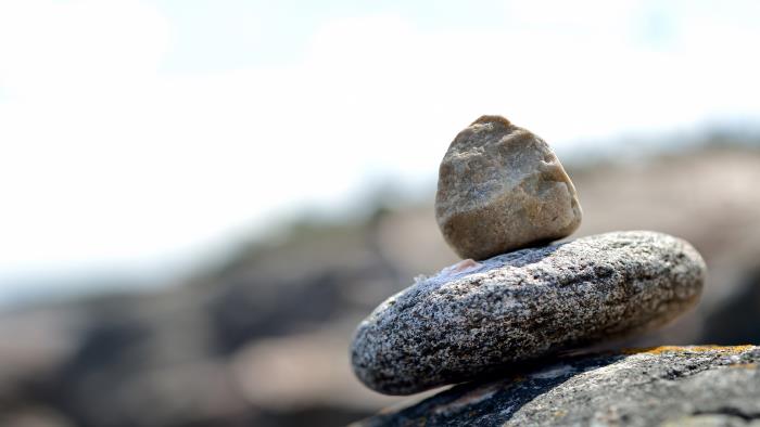 Två stenar balanserar på varandra på en klippa.