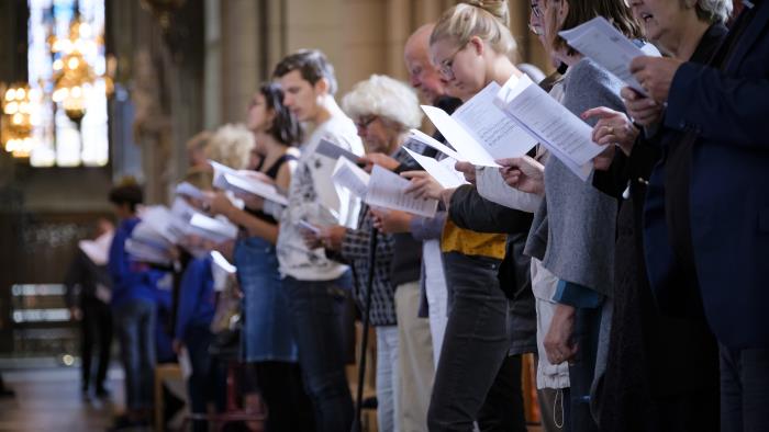En rad människor står med sånghäften och sjunger i Uppsala domkyrka.