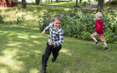 Två pojkar springer runt på gräset.