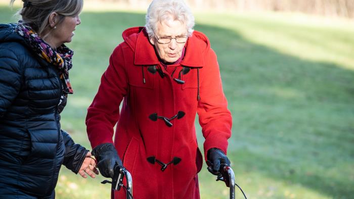 En yngre och en äldre kvinna ute på promenad, den äldre går med en rollator.