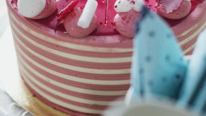 Närbild på tårta dekorerad med olika rosa detaljer.