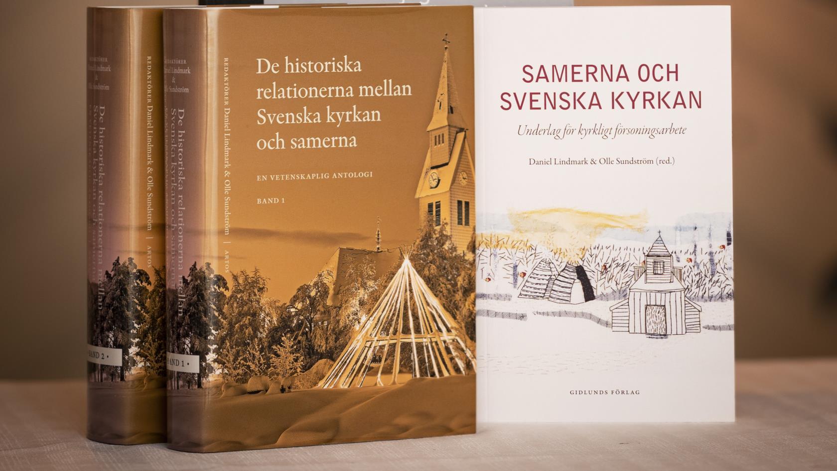 Tre böcker om Svenska kyrkan och samerna står uppställda på ett bord.
