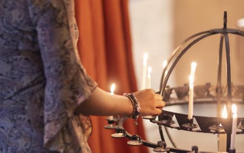 En kvinna sätter ett tänt ljus i en ljusbärare.