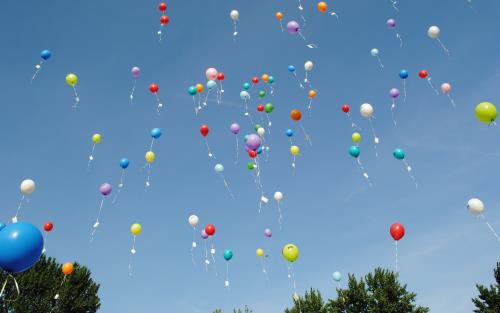 Ballonger som svävar upp mot en blå himmel.