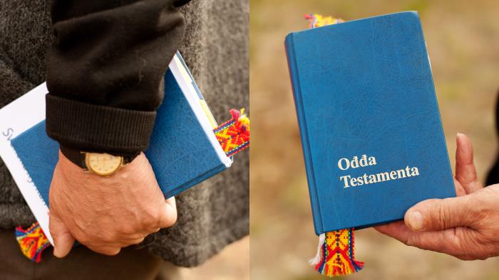 En person går och bär på en samisk utgåva av gamla testamentet.