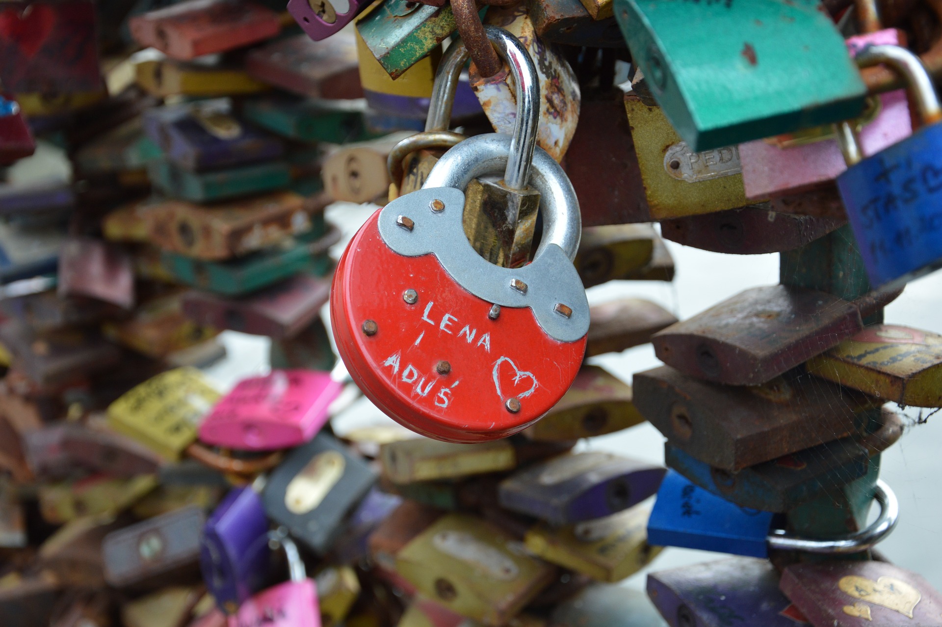 Ett rött hänglås i form av ett hjärta och två namn skrivna på låset.