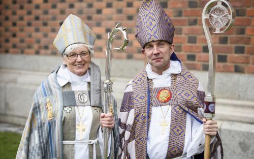 Porträttbild på ärkebiskop Antje Jackelén och biskop Fredrik Modéus i ämbetsdräkter och med kräklor i handen.