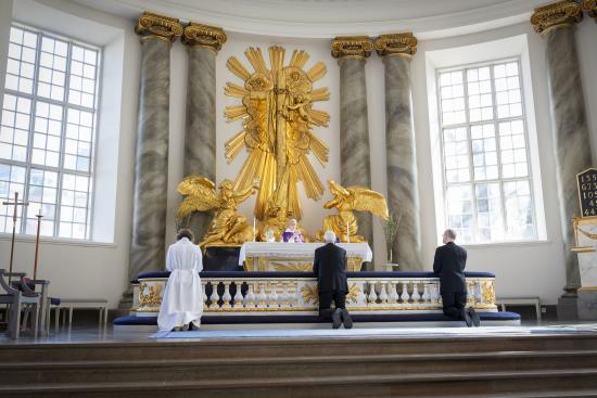 Tre personer knäböjer framför altaret i Domkyrka i Göteborg.