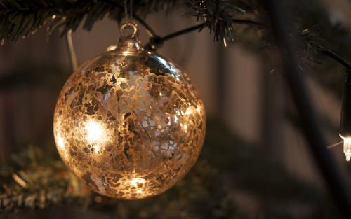 En guldfärgad julgranskula hänger i granen.