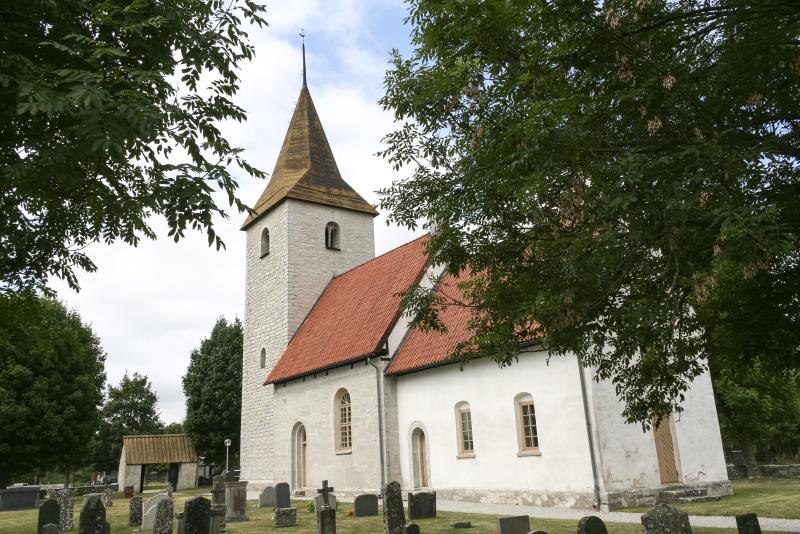 En vit kyrka i sten och en kyrkogård.