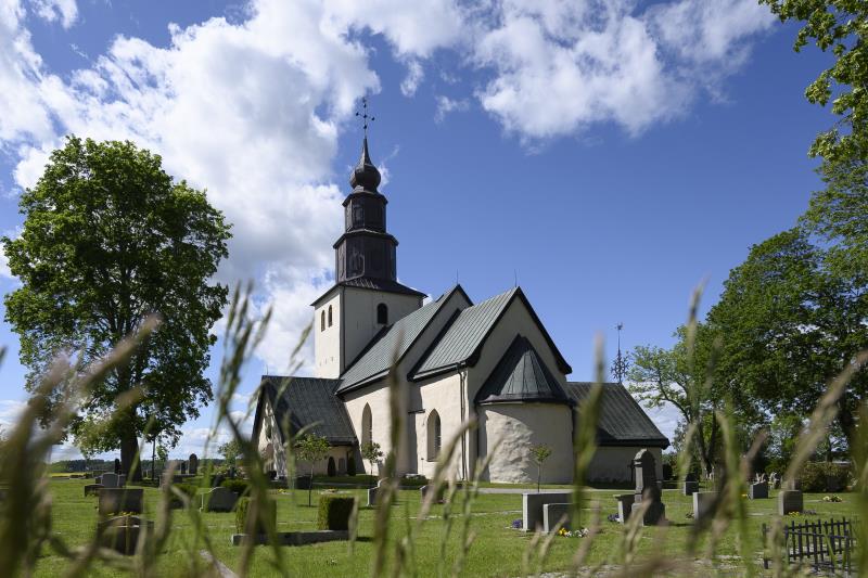 En kyrka och en kyrkogård en solig sommardag.