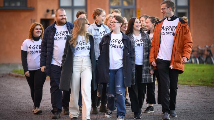 En grupp glada personer går tätt ihop och pratar med personen bredvid. 