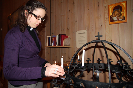 Prästen Madeleine Dahl sätter ett tänt ljus i en ljushållare