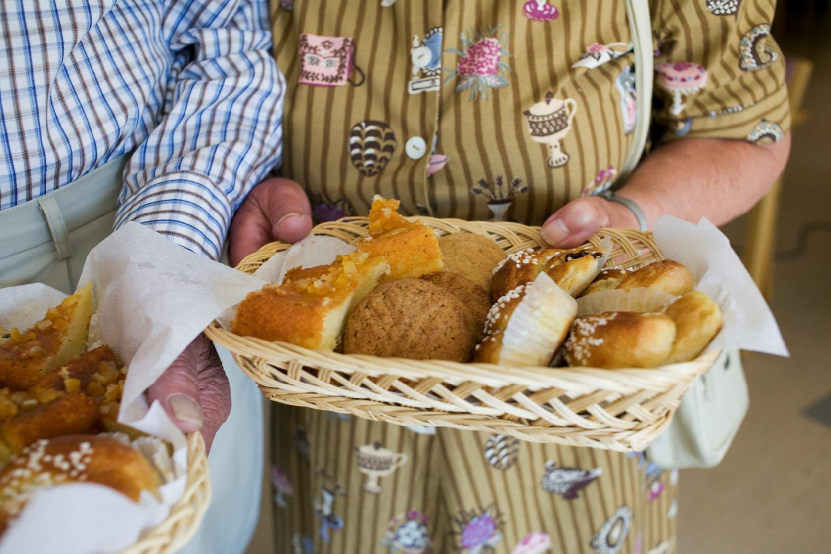 Ett fat med kakor i händerna på två människor.