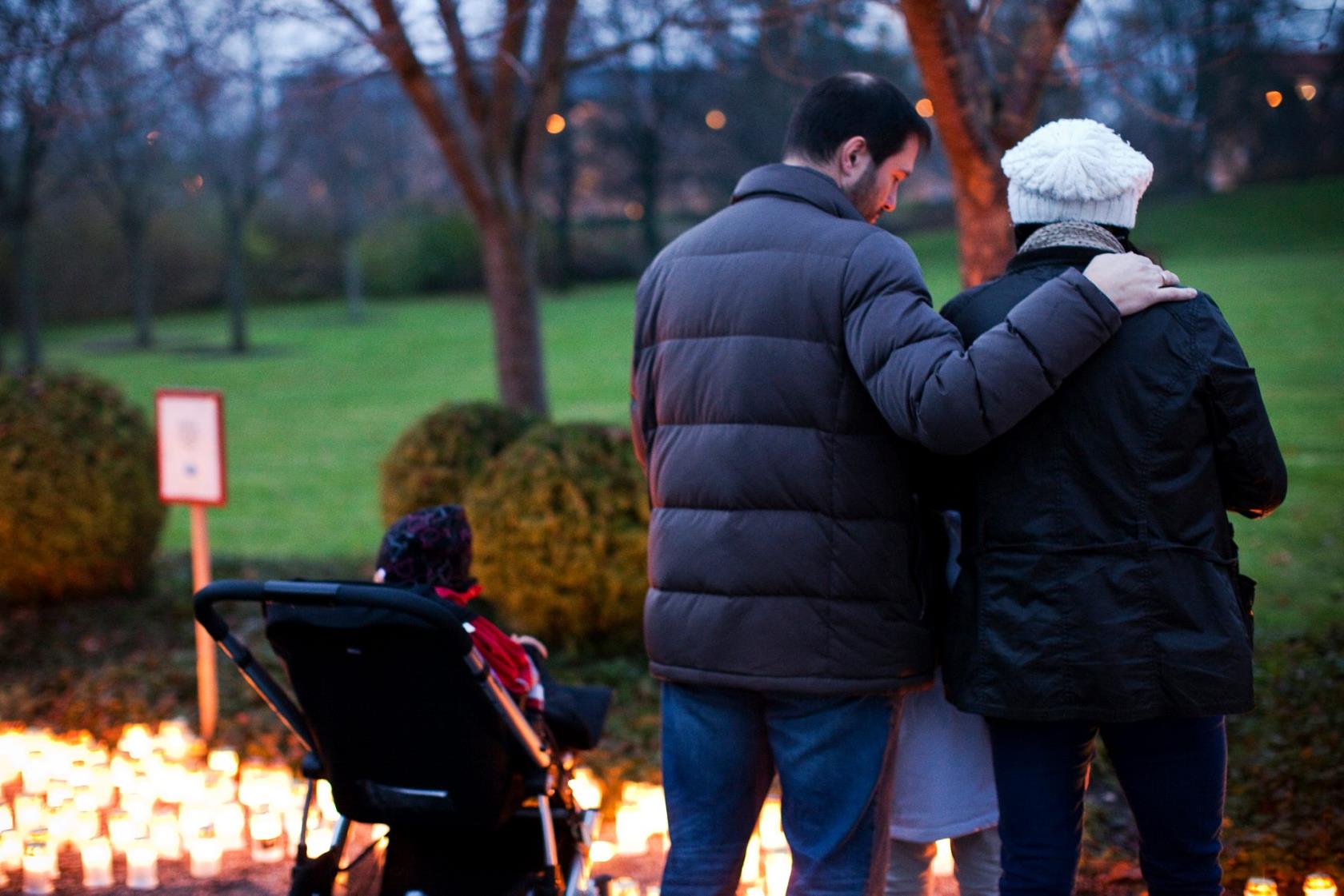 Familj som tänder ljus på kyrkogården.