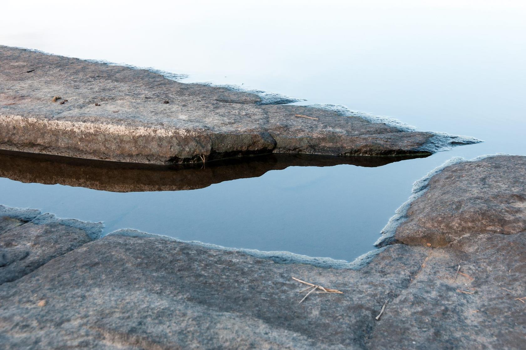 En klippskreva med vatten. Utanför syns havet.