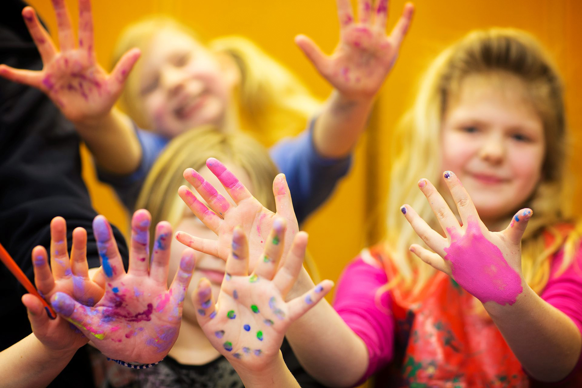 Glada barn sträcker fram händerna målade med fingerfärger