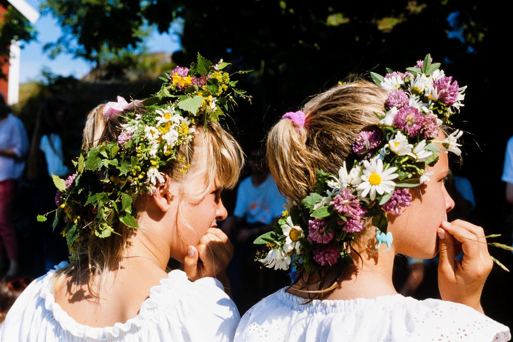 Två flickor med midsommarkransar på huvudet.