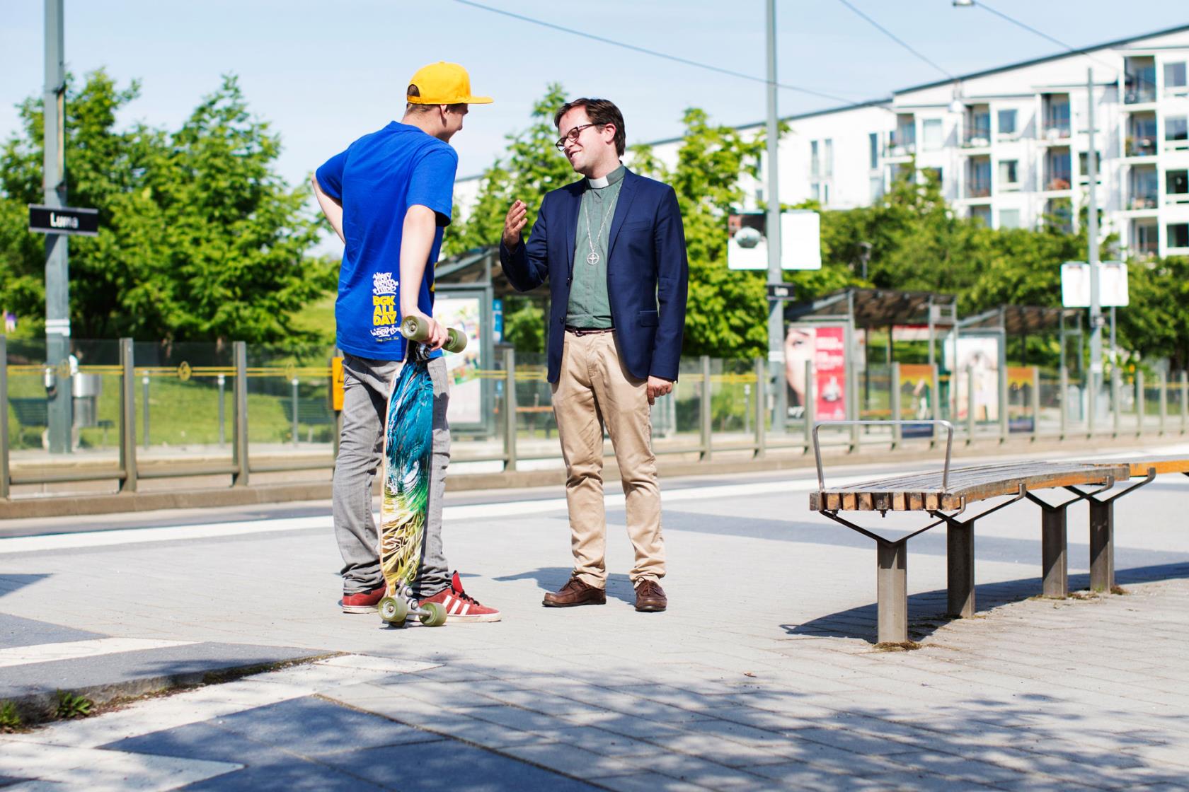 Präst och kille med skateboard pratar