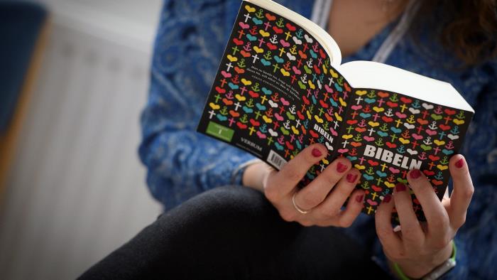 En person läser en bibel med färggrant omslag