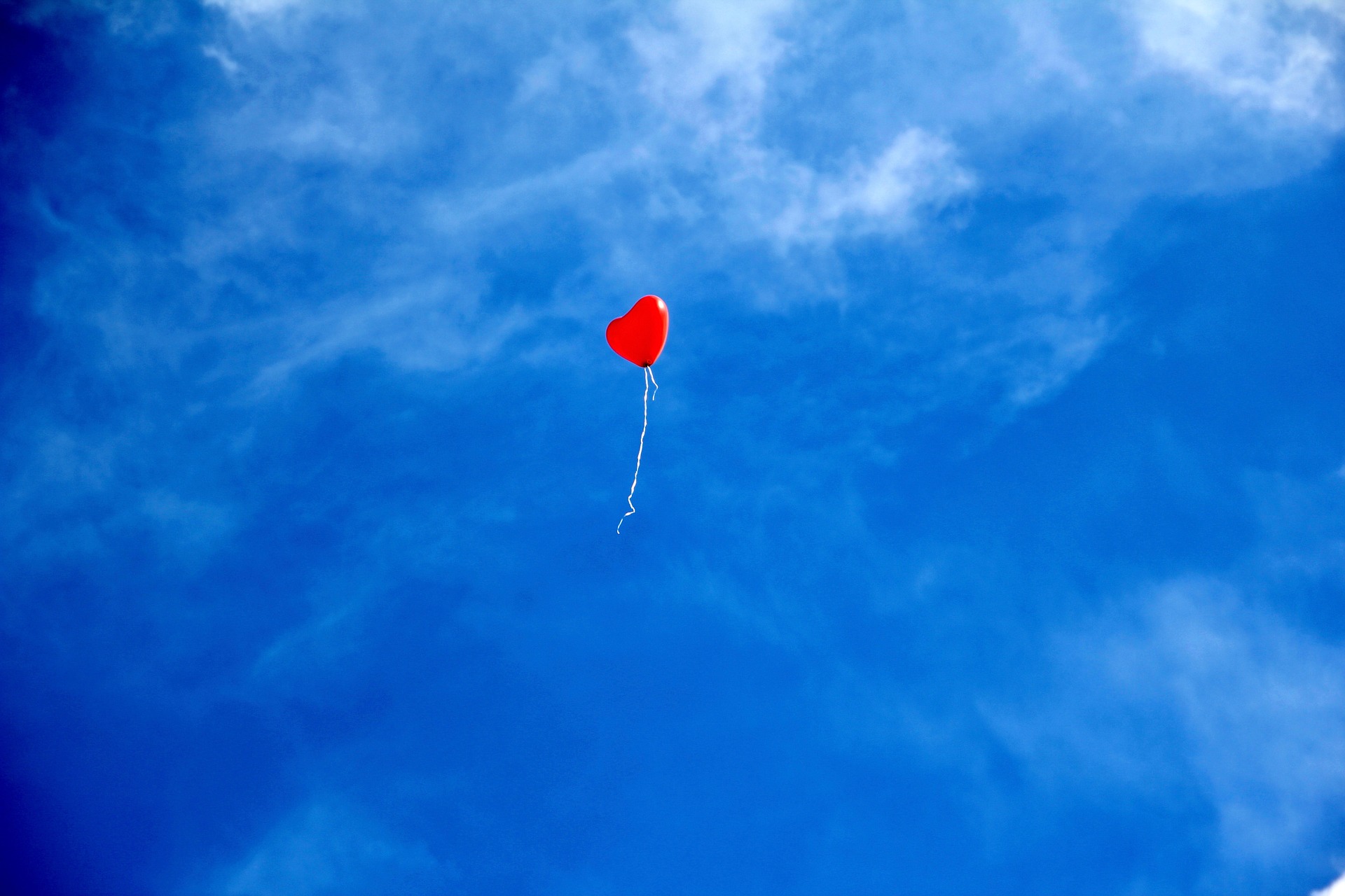 Hjärtformad röd ballong mot blå himmel