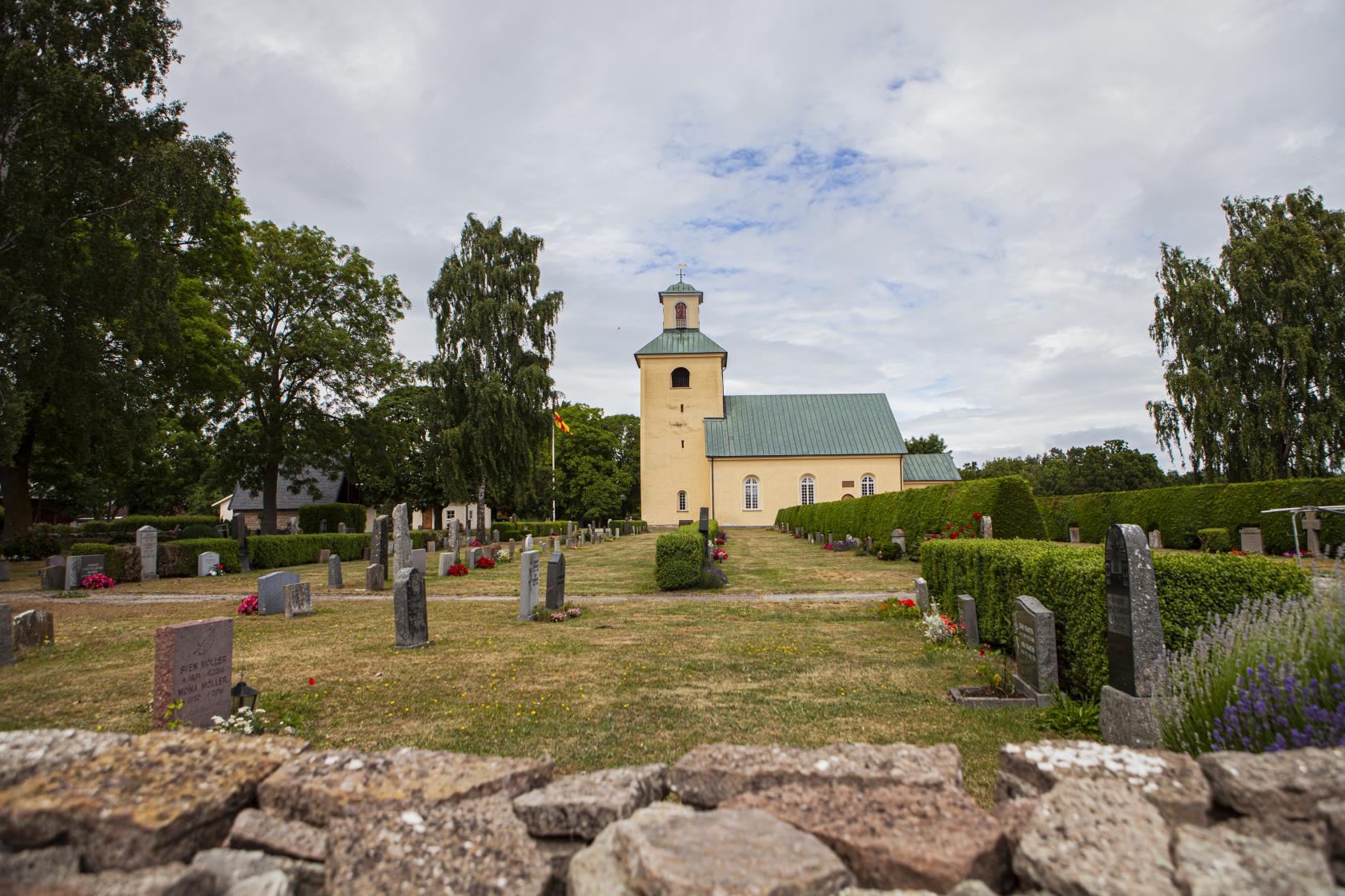 Gul kyrka med kyrkogård framför