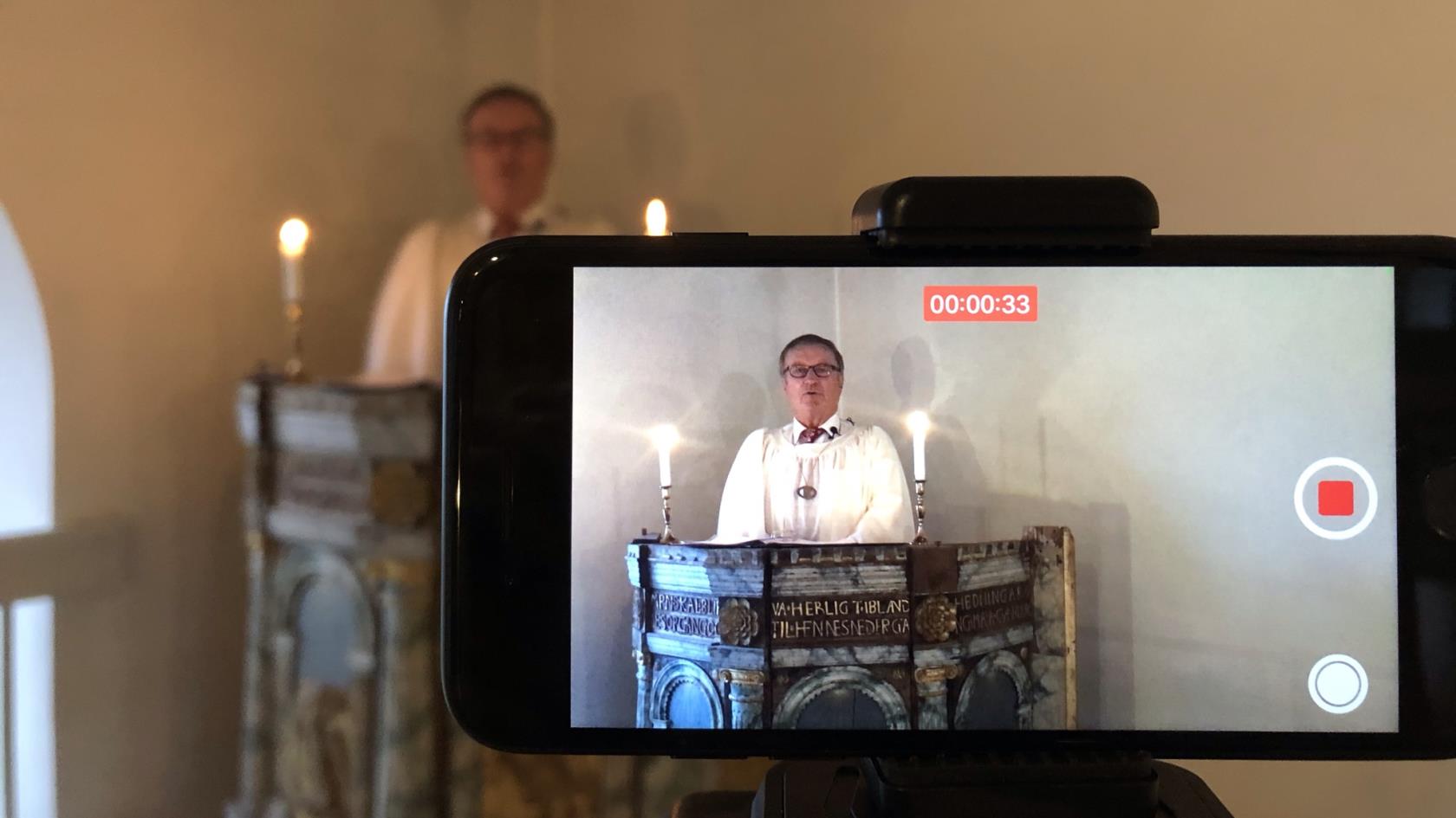 Johan Barkevall predikar i den gamla predikstolen i Högby kyrka framför en telefonkamera