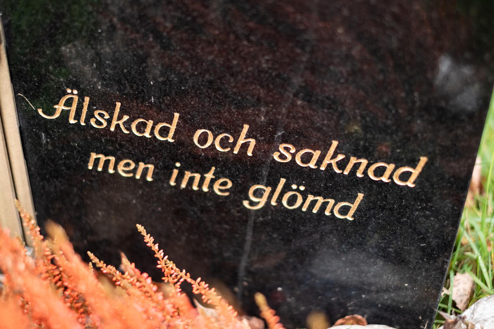 Svart gravsten med guldtext som säger "Älskad och saknad med inte glömd". 