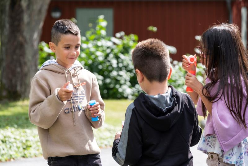 Barn blåser såpbubblor i solen