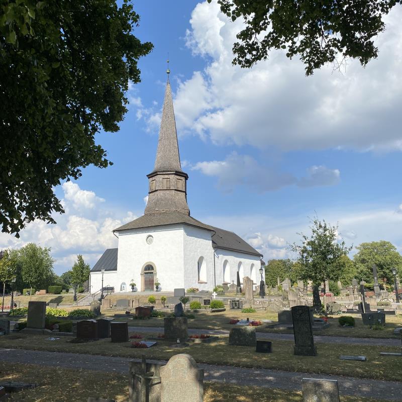 Söndrums kyrka, sensommar, men gröna blad i förgrunden.