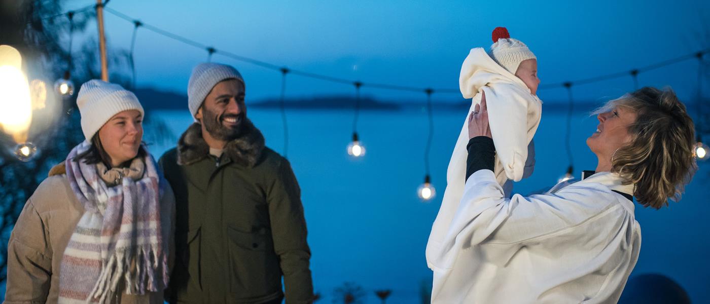 Ett föräldrapar, en präst och en bebis vid ett dop utomhus på vintern.