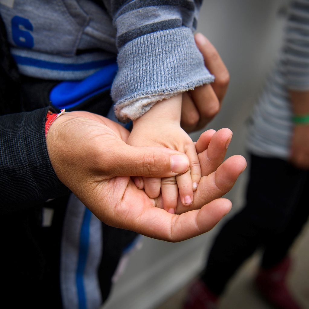 En vuxen håller ett barns hand i sin.