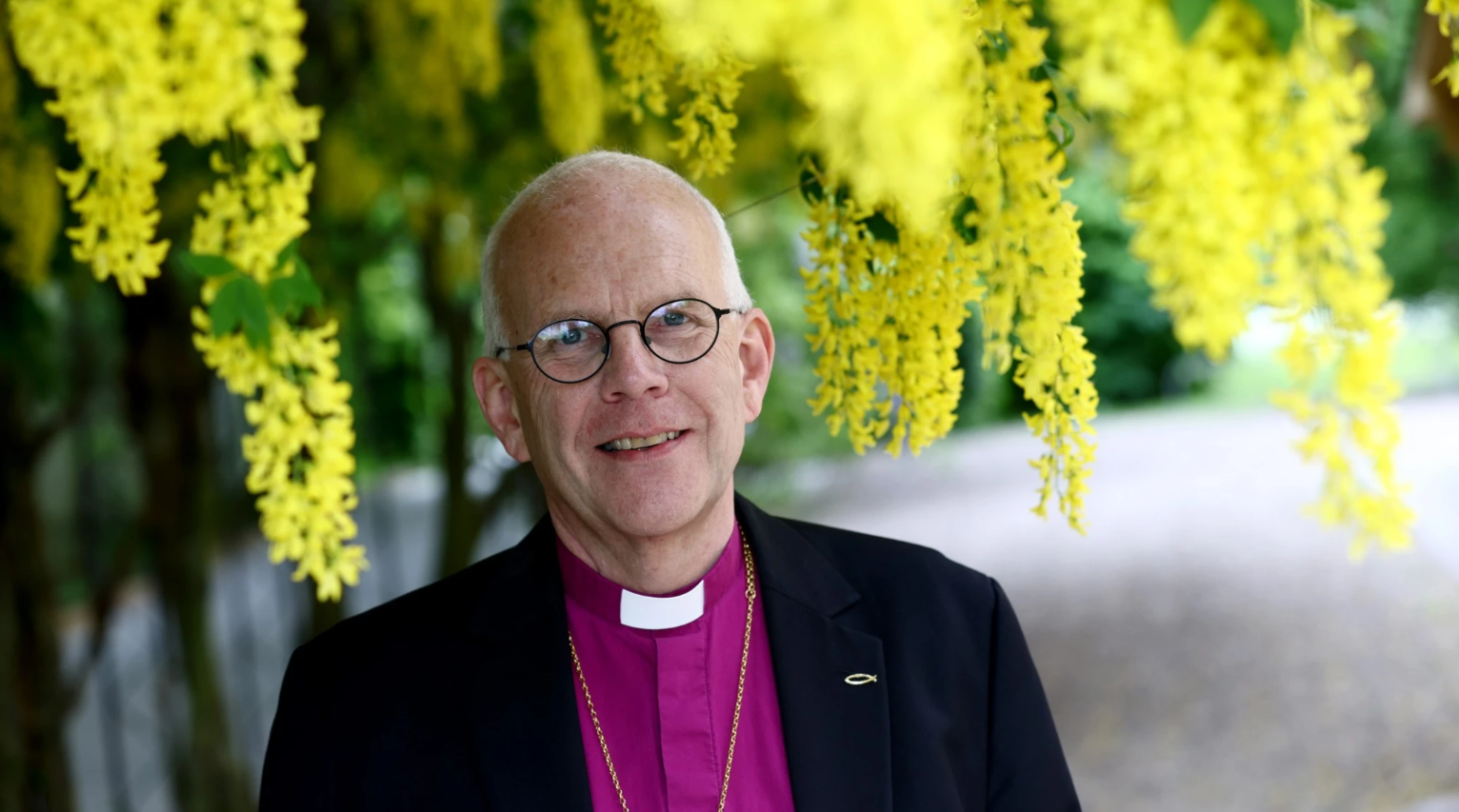 Ärkbiskop Martin står i lila biskopsskjorta och kavaj.