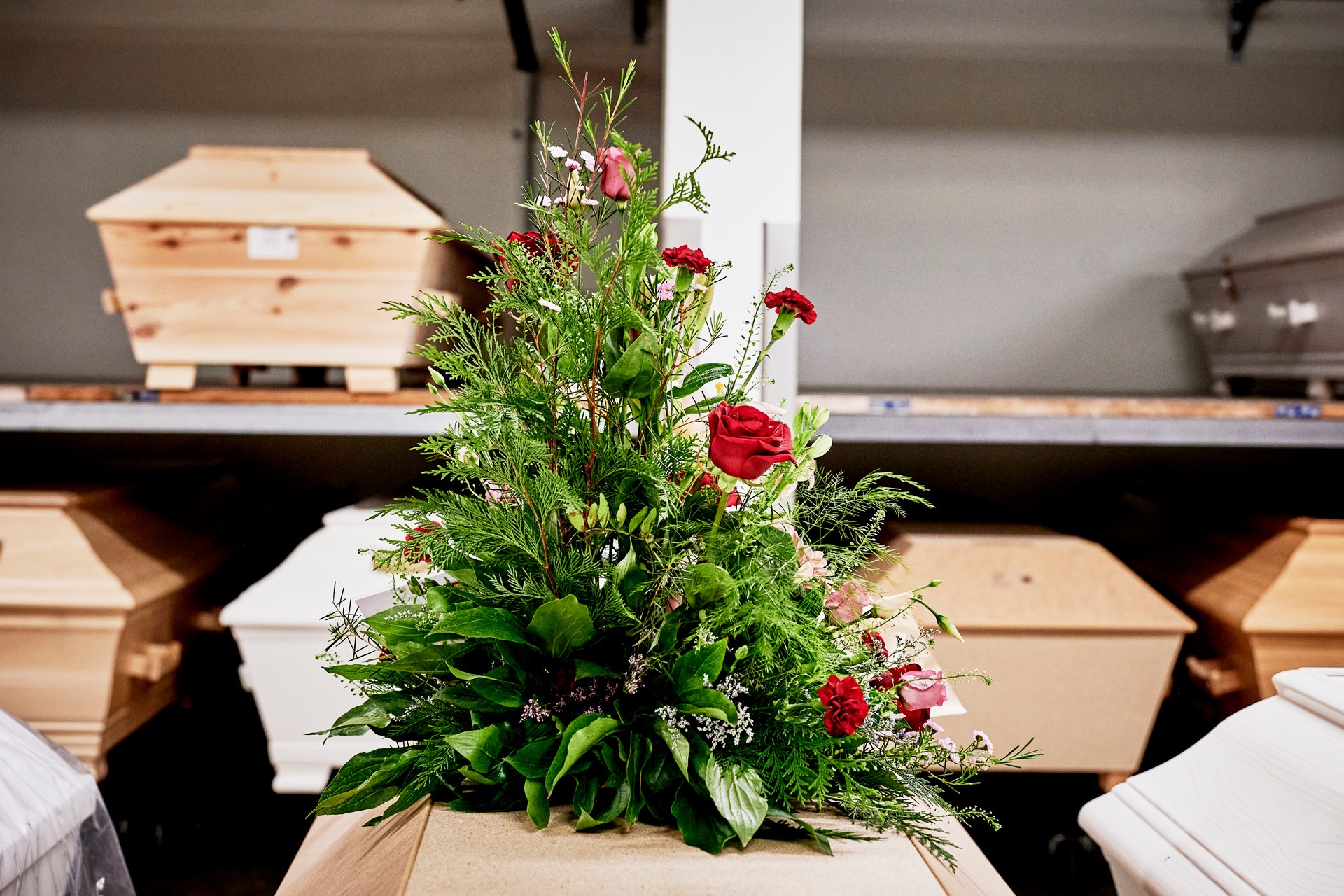 Kistor i bisättningsrummet på Berthåga krematorium. En av kistorna har ett blomsterarrangemang placerat ovanpå kistlocket. 