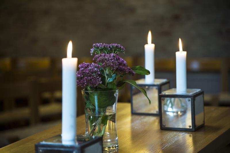 Ljusstakar med tända ljus och en vas med blommor 