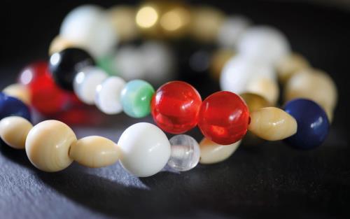 Armband med pärlor i guld, rött, grönt, beige och blå.