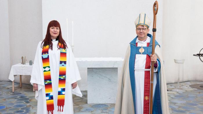 Kvinnlig präst med färgrik stola och manlig biskop med kräkla och mitra.