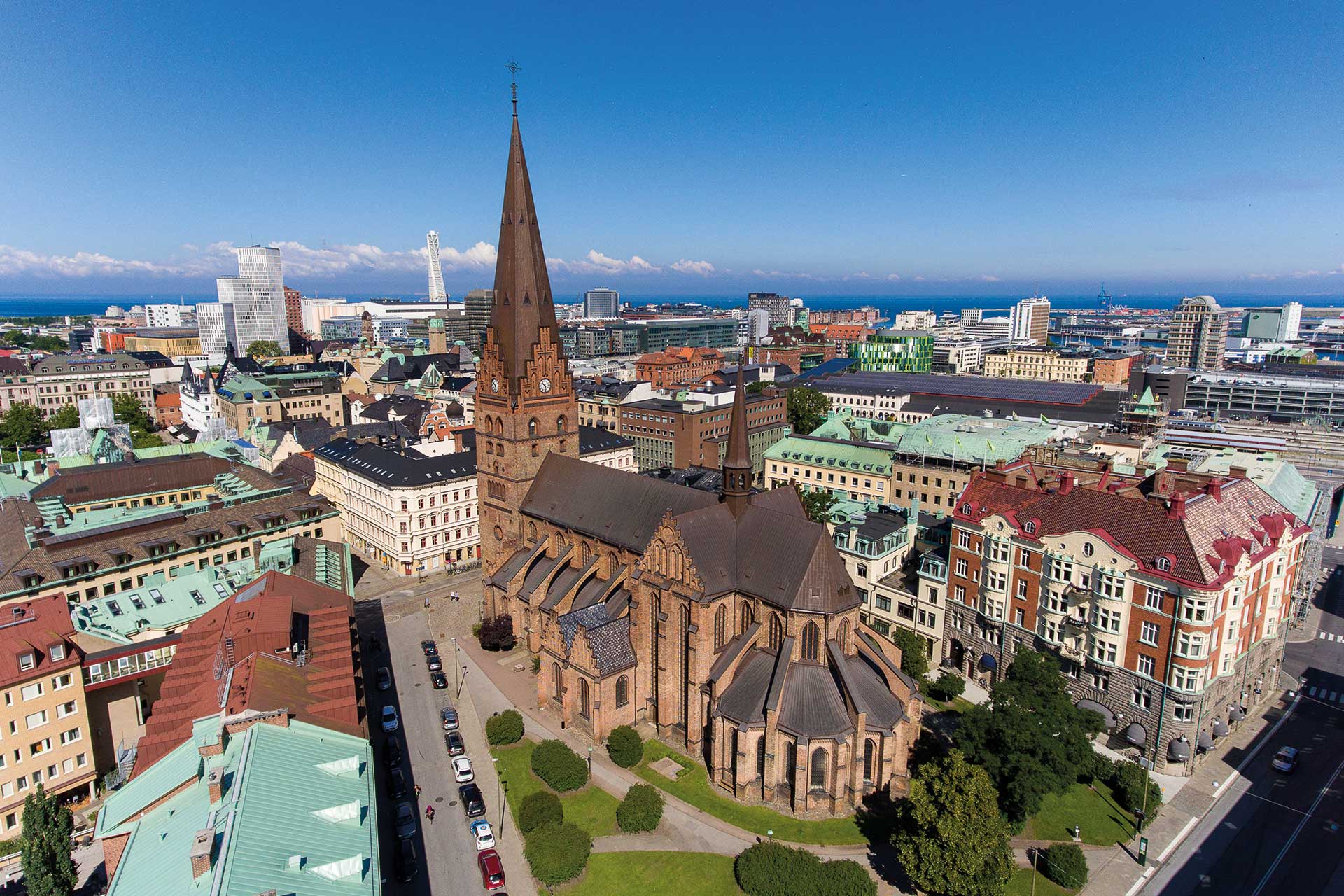 Flygbild över S:t Petri kyrka under en klarblå himmel och med Turning Torso i bakgrunden.