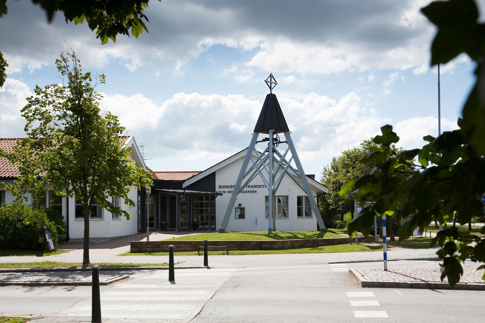 Bunkeflo Strandkyrka är en trelängad låg, vit tegelbyggnad med en fristående klockstapel utanför.