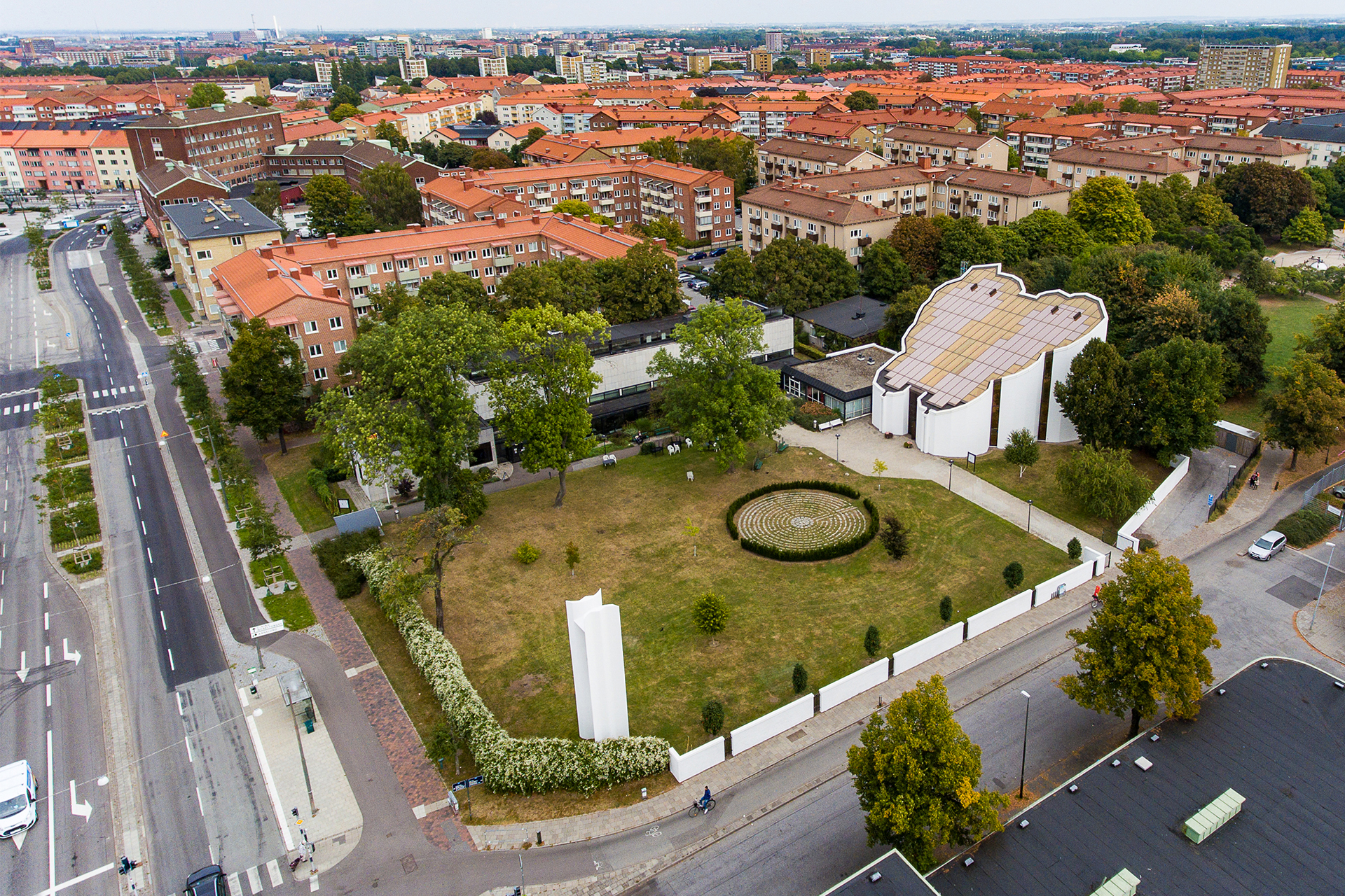 En flygbild över S:t Matteus kyrka och församlingshuset vid Matteusparken som omgärdas av en manshög vit mur utåt Ystadsgatan och Lantmannagatan.